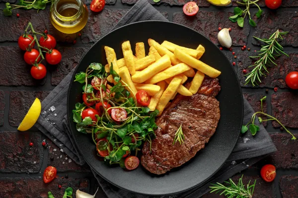 Steak mit Beilagen auf einem schwarzen Teller